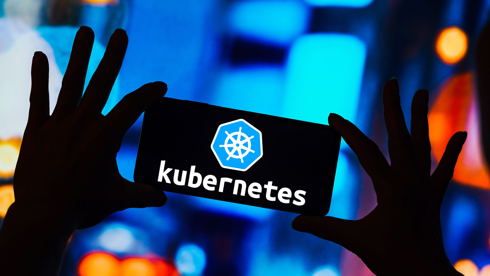 Hands holding a phone with the Kubernetes logo